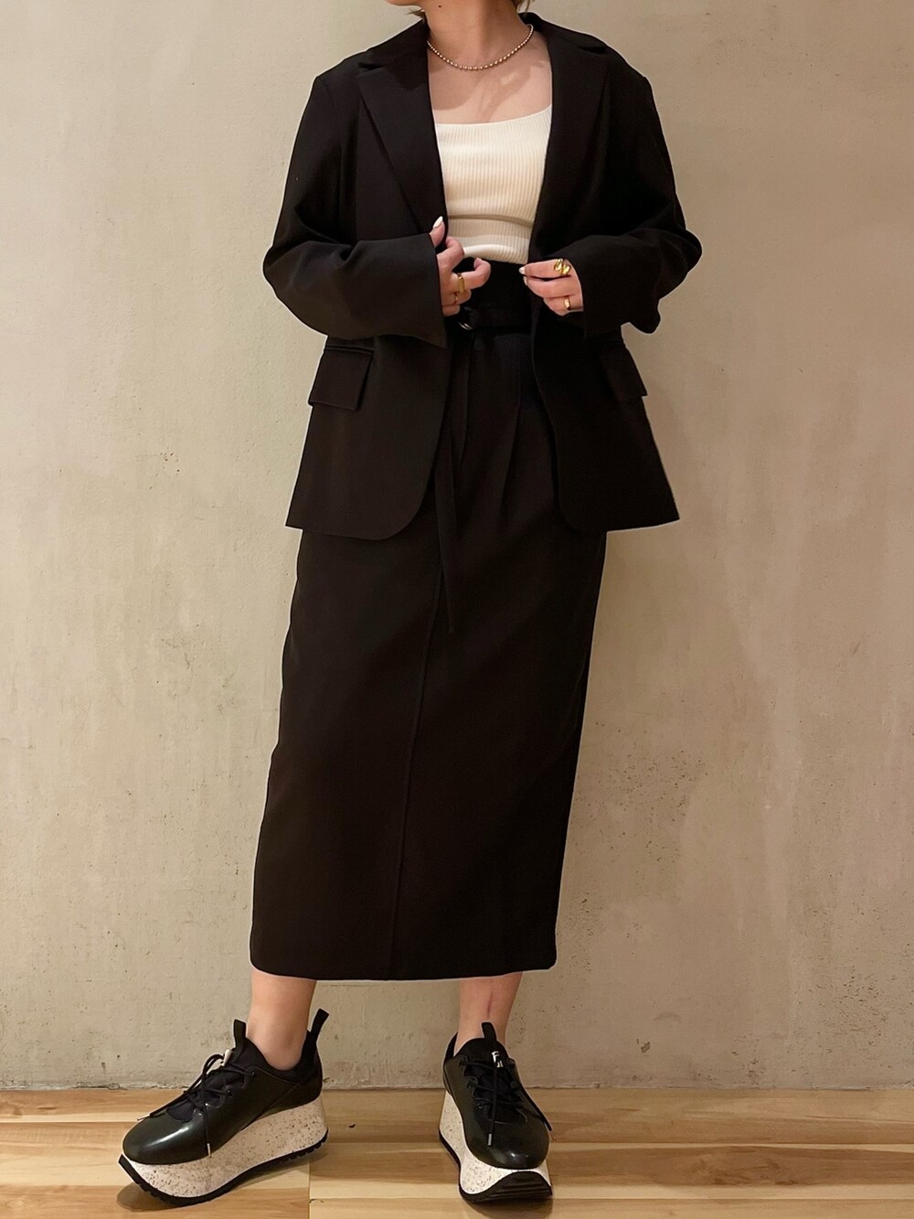 ブラック系のテーラードジャケット、ブラック系のスカート、ブラック系のスニーカーを着用したレディースの冬コーディネートの3枚目の写真