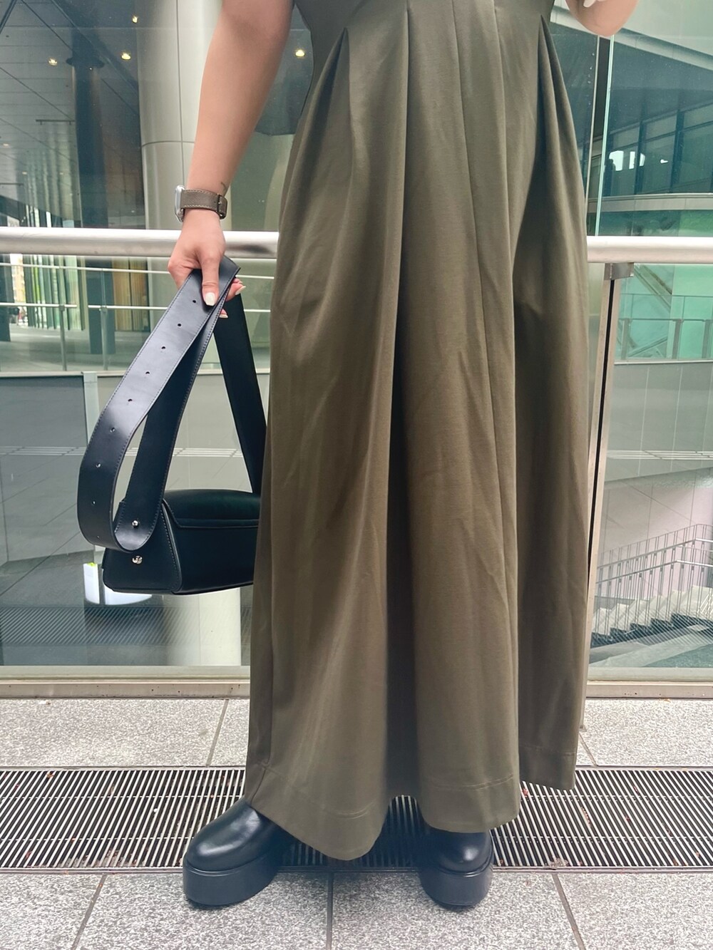 グリーン系のワンピース、ブラック系のブーツ、ブラック系のショルダーバッグを着用したレディースの春コーディネートの7枚目の写真