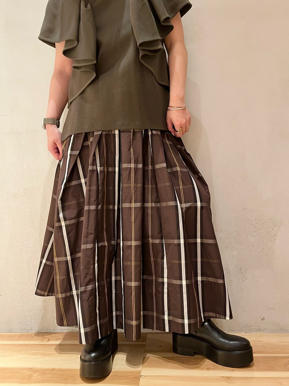 ブラック系のブーツ、グリーン系のTシャツ/カットソー、ブラウン系のスカートを着用したレディースの春コーディネートの6枚目の写真