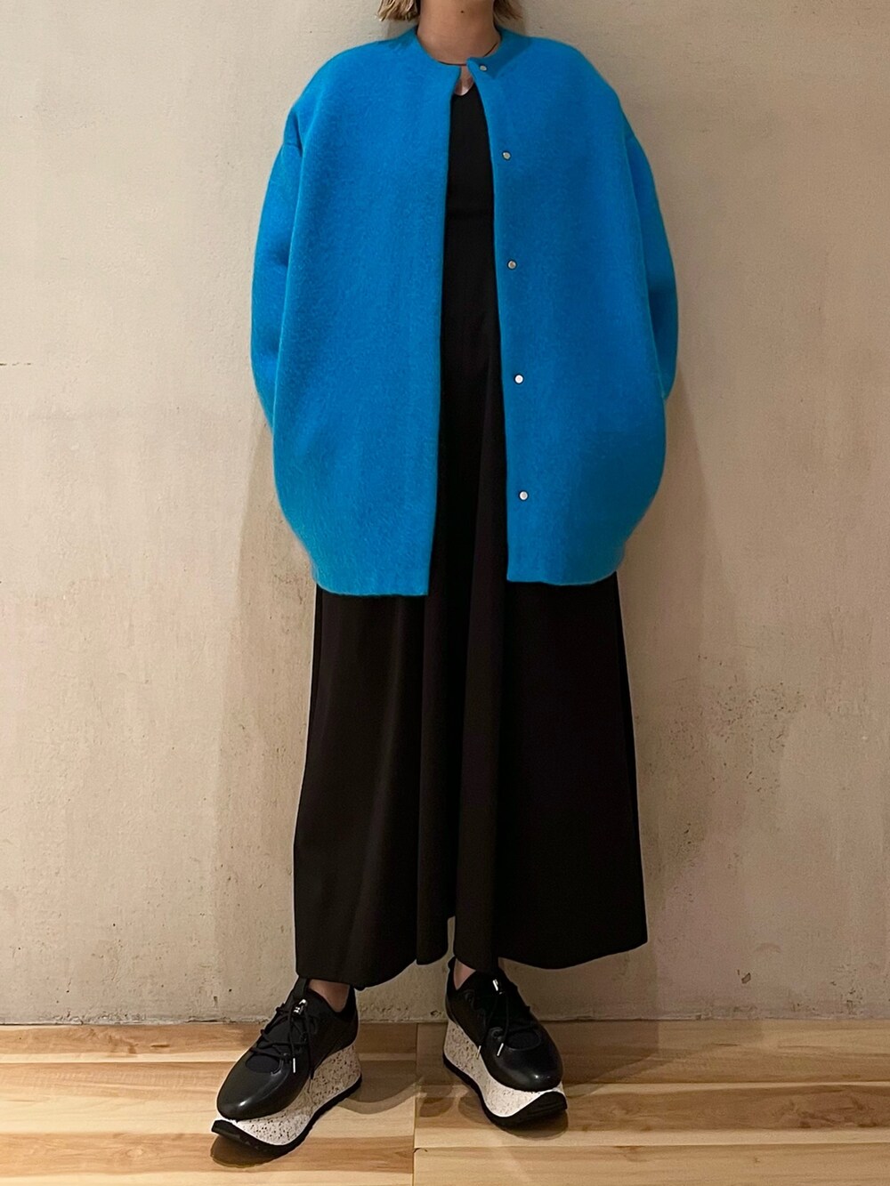 ブルー系のノーカラージャケット、ブラック系のワンピース、ブラック系のスニーカーを着用したレディースの夏コーディネートの5枚目の写真