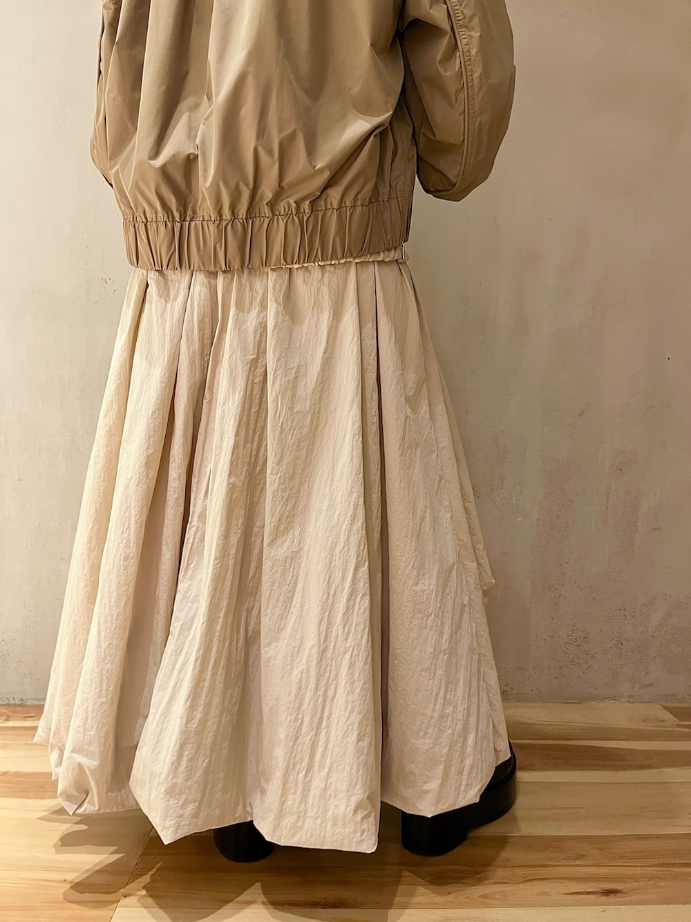 ベージュ系のブルゾン、ベージュ系のワンピース、ブラック系のブーツを着用したレディースの夏コーディネートの8枚目の写真