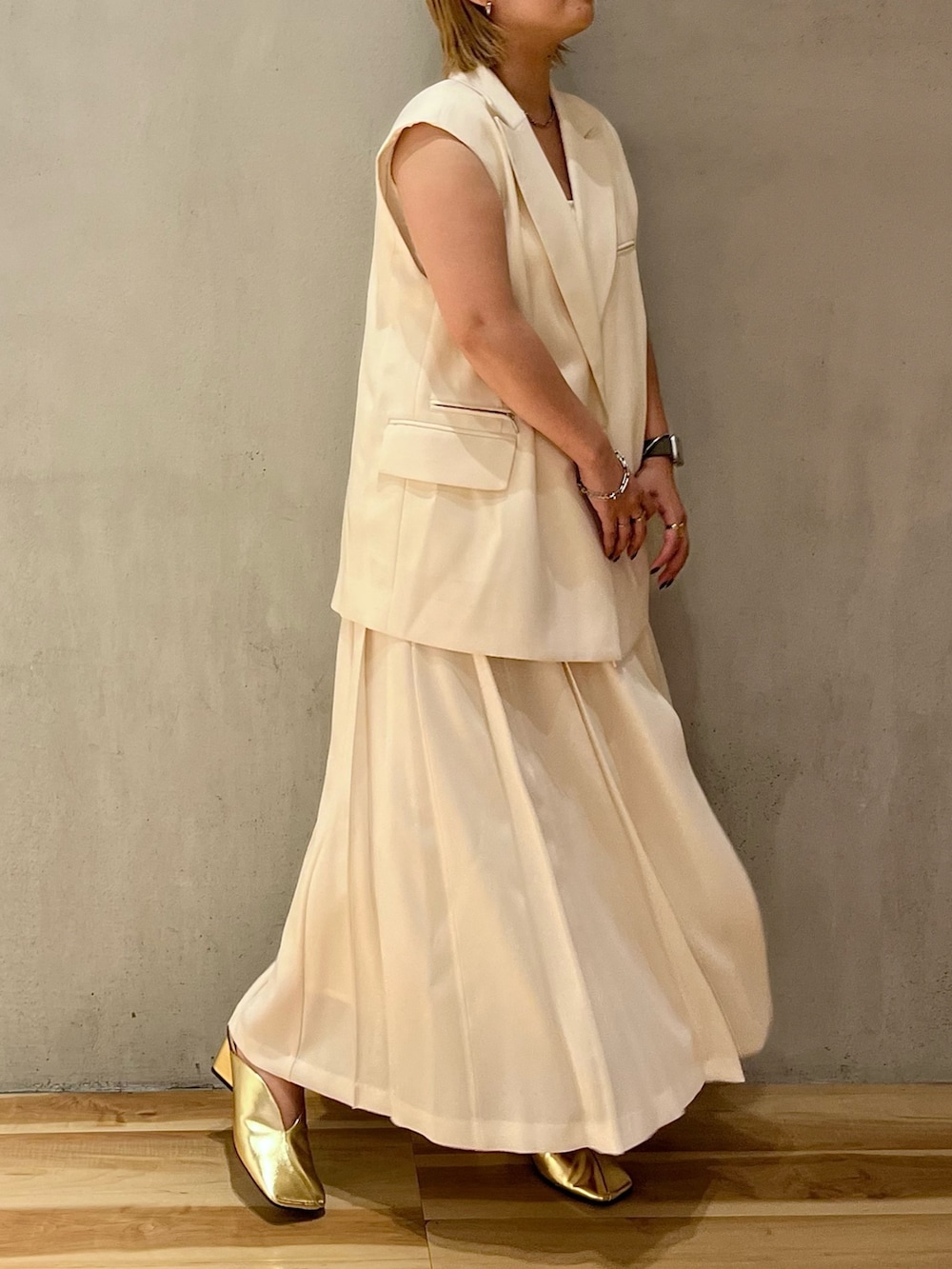 ゴールド系のパンプス、ホワイト系のスカート、ホワイト系のタンクトップを着用したレディースの冬コーディネートの2枚目の写真