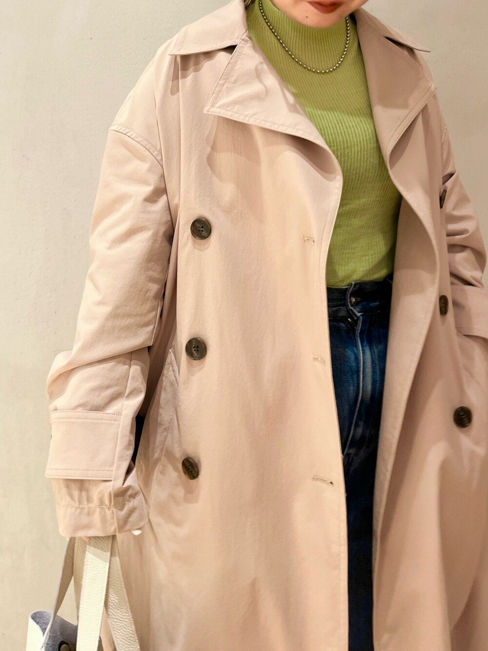 グリーン系のニット/セーター、ベージュ系のトレンチコート、ブルー系のデニムパンツを着用したレディースの冬コーディネートの5枚目の写真