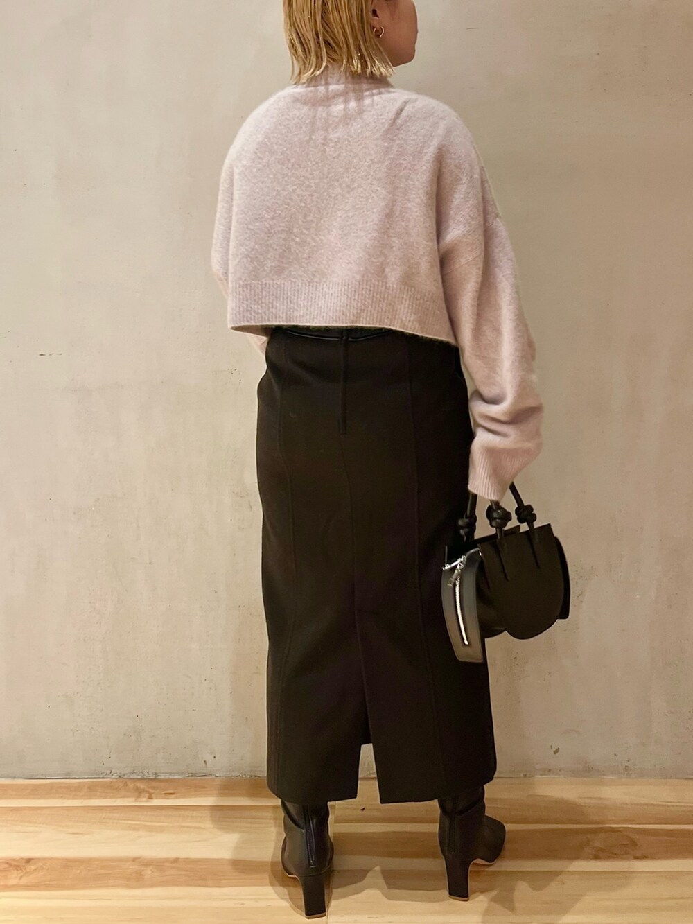 ブラック系のスカート、ブラック系のブーツ、ブラック系のハンドバッグを着用したレディースの秋コーディネートの3枚目の写真