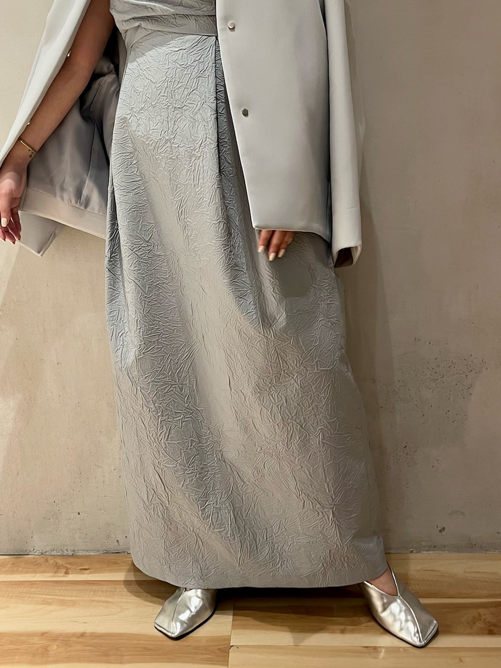 ブルー系のノーカラーコート、シルバー系のパンプス、ブルー系のワンピースを着用したレディースの冬コーディネートの8枚目の写真