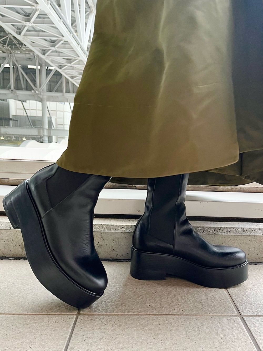 ホワイト系のシャツ/ブラウス、グリーン系のジャンパースカート、ブラック系のブーツを着用したレディースの春コーディネートの8枚目の写真