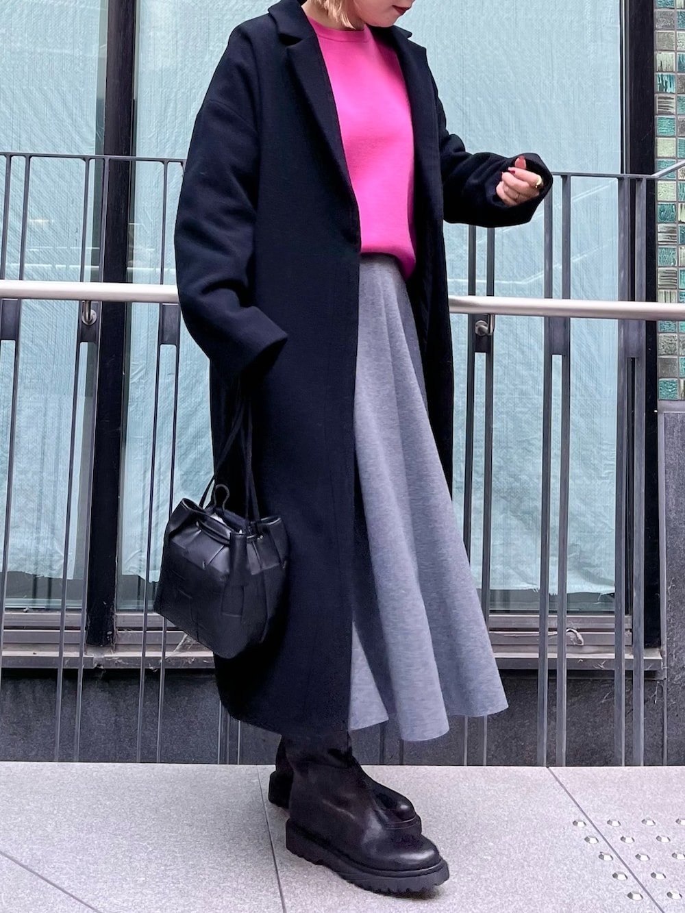 ピンク系のニット/セーター、ブラック系のチェスターコート、グレー系のスカートを着用したレディースの冬コーディネートの4枚目の写真