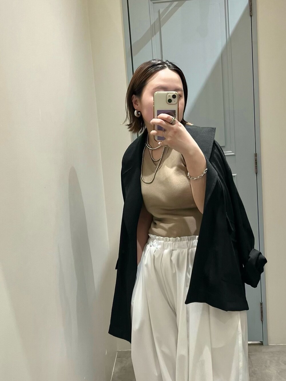 ブラック系のテーラードジャケット、ベージュ系のニット/セーター、ホワイト系のその他パンツを着用したレディースの春コーディネートの6枚目の写真