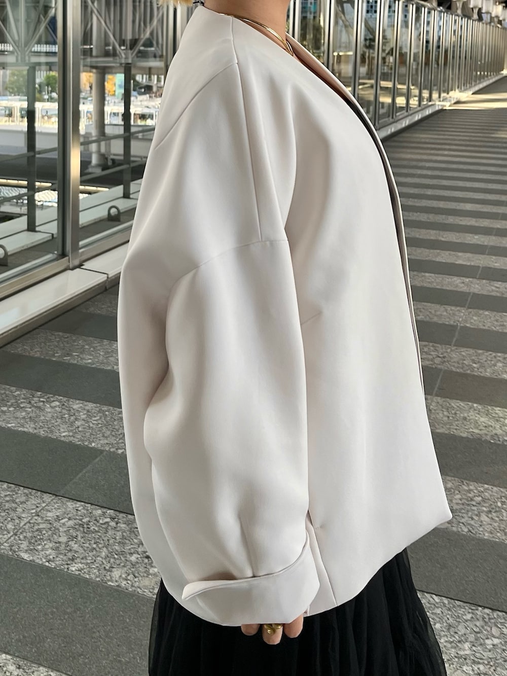 ベージュ系のノーカラーコート、ブラック系のタンクトップ、ブラック系のスカートを着用したレディースの冬コーディネートの7枚目の写真