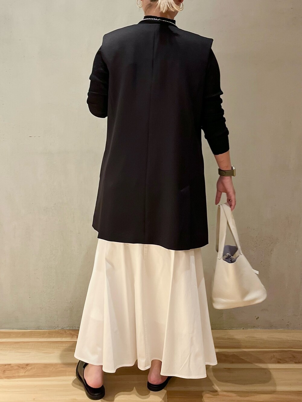 ホワイト系のスカート、ホワイト系のハンドバッグ、ブラック系のテーラードジャケットを着用したレディースの冬コーディネートの3枚目の写真