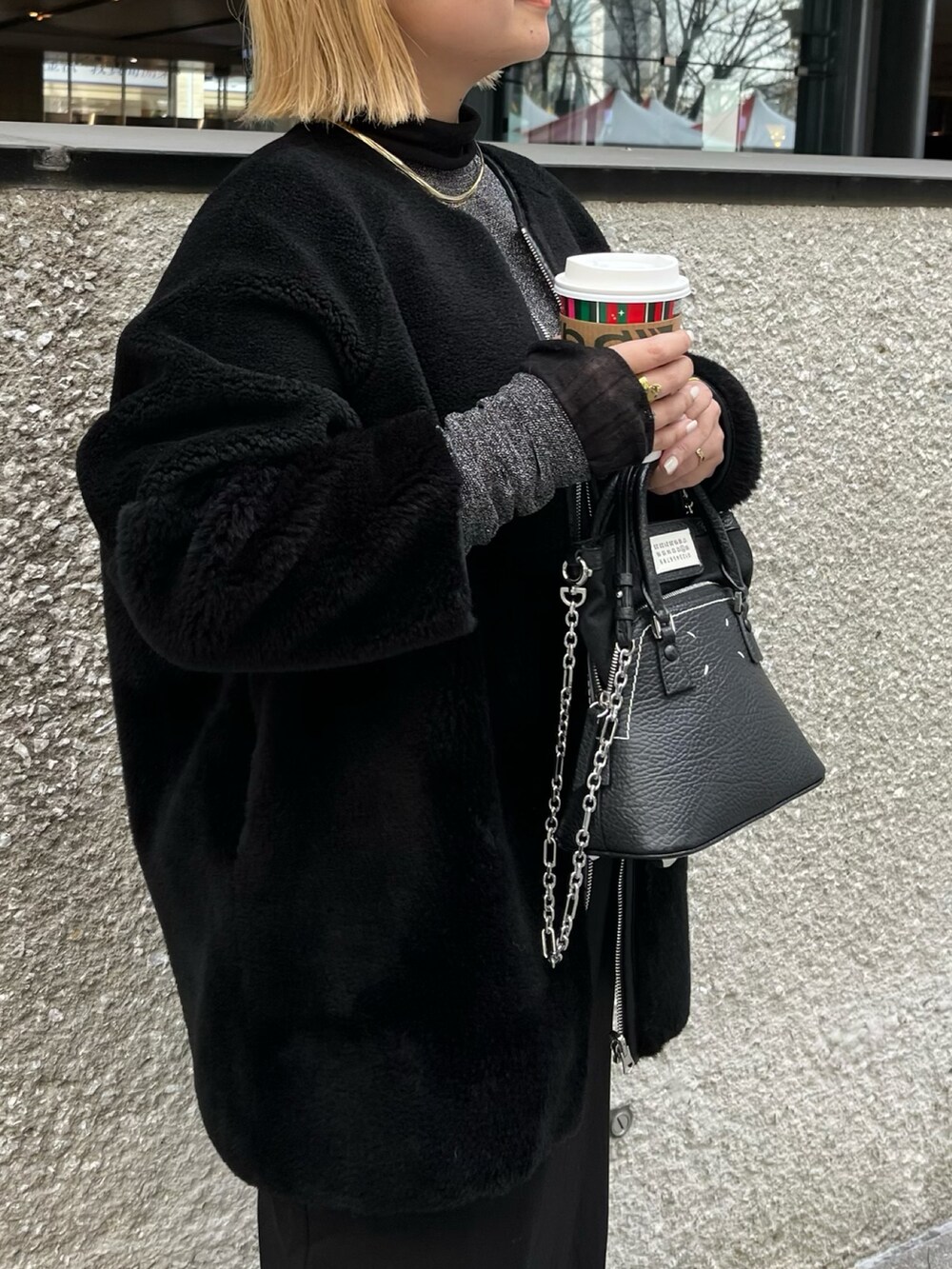 ブラック系のノーカラーコート、シルバー系のTシャツ/カットソー、ブラック系のブーツを着用したレディースの冬コーディネートの5枚目の写真