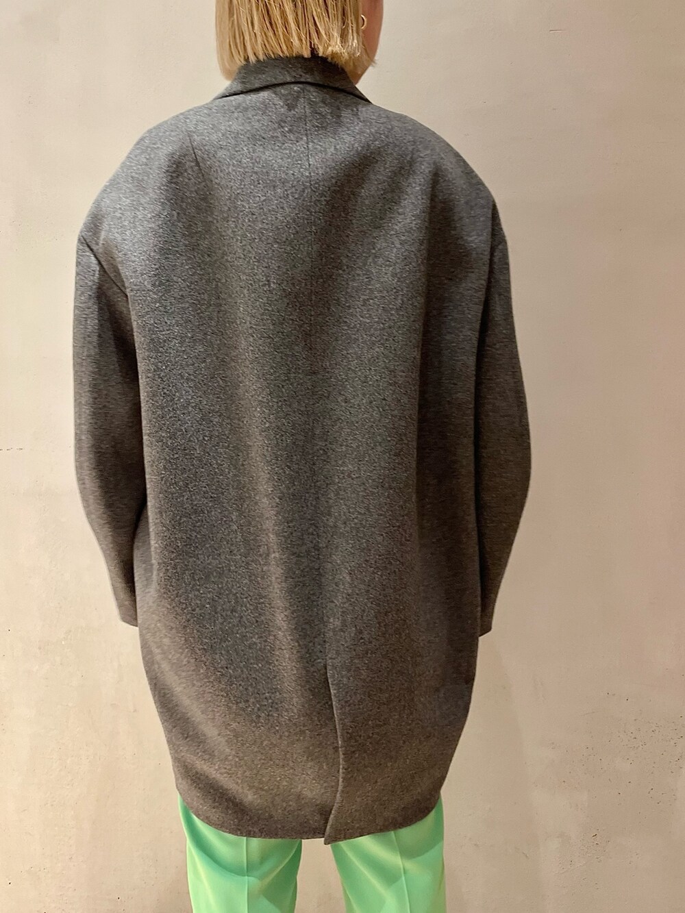 グレー系のチェスターコート、グリーン系のその他パンツ、シルバー系のTシャツ/カットソーを着用したレディースの秋コーディネートの5枚目の写真