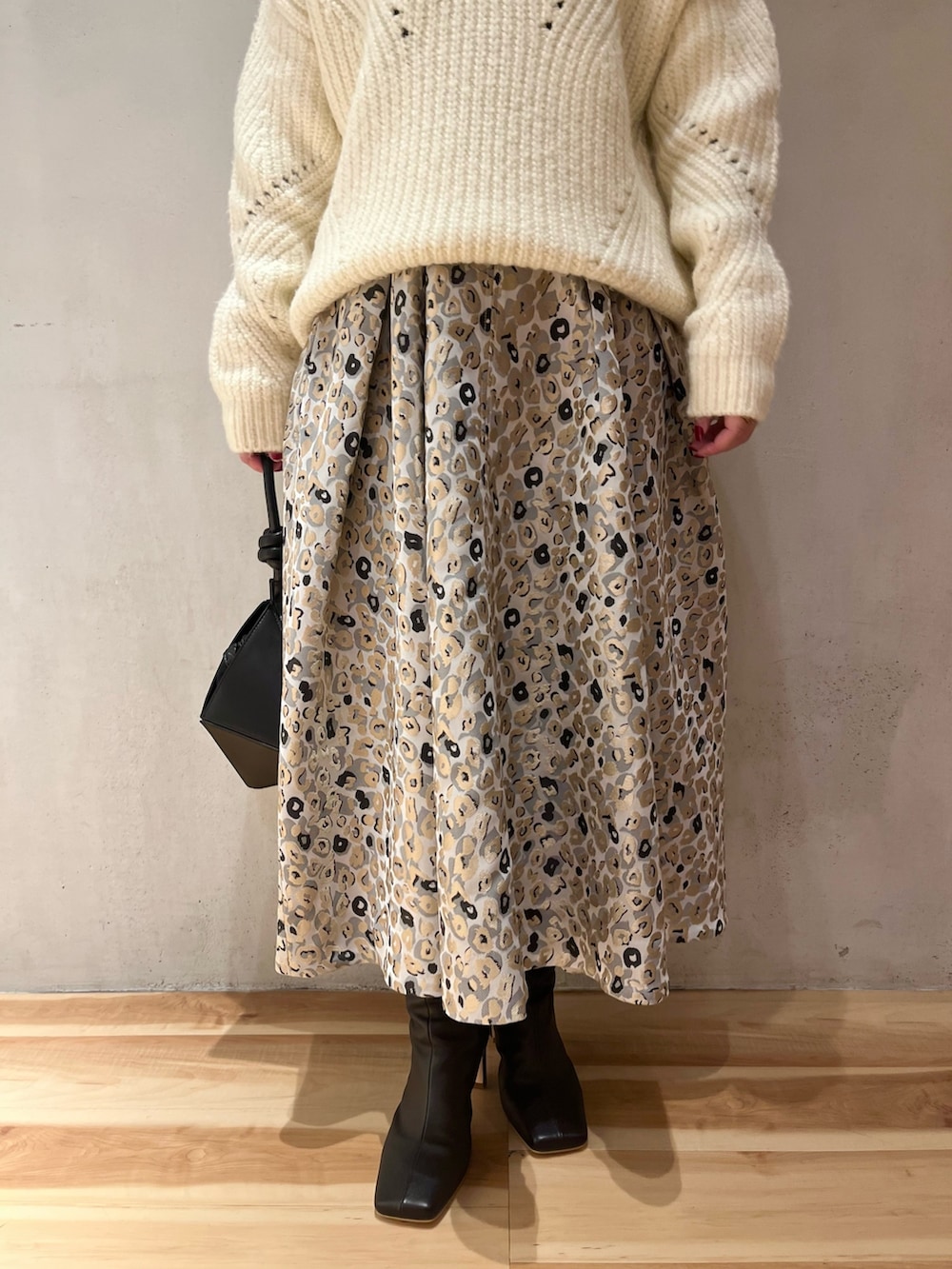 ベージュ系のスカート、ブラック系のハンドバッグ、ホワイト系のニット/セーターを着用したレディースの冬コーディネートの7枚目の写真