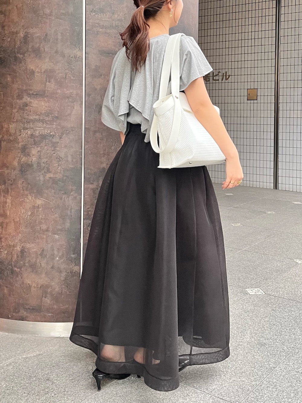 グレー系のTシャツ/カットソー、ブラック系のスカート、ブラック系のパンプスを着用したレディースの春コーディネートの3枚目の写真