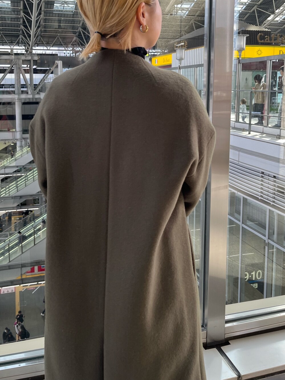 グリーン系のノーカラーコート、グレー系のその他パンツ、ブラック系のハンドバッグを着用したレディースの冬コーディネートの7枚目の写真