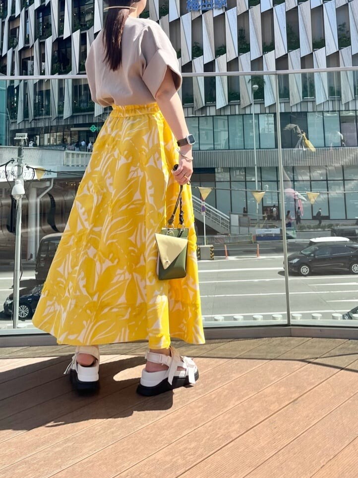 イエロー系のショルダーバッグ、イエロー系のスカート、ホワイト系のサンダルを着用したレディースの春コーディネートの2枚目の写真