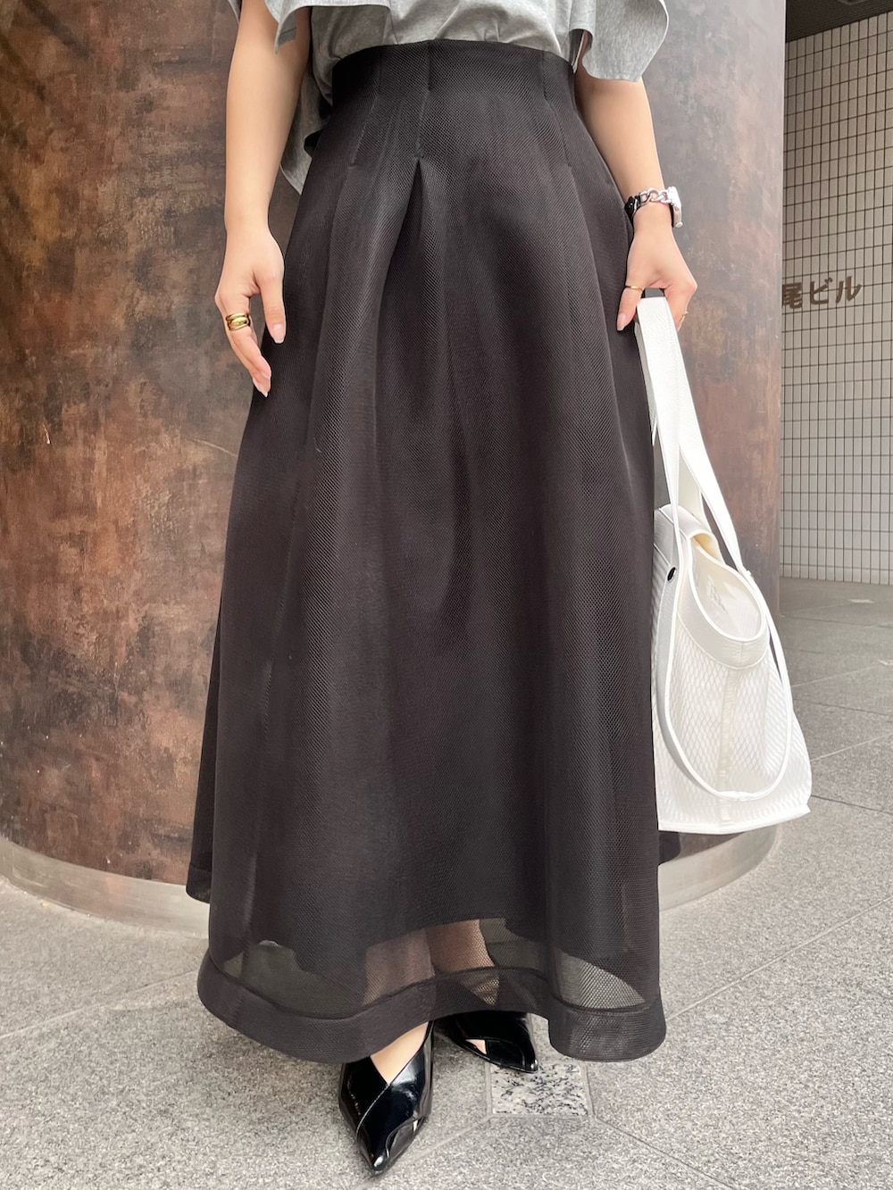 グレー系のTシャツ/カットソー、ブラック系のスカート、ブラック系のパンプスを着用したレディースの春コーディネートの7枚目の写真