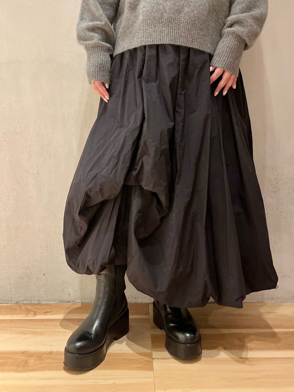 グレー系のニット/セーター、ブラック系のスカート、ブラック系のブーツを着用したレディースの冬コーディネートの8枚目の写真