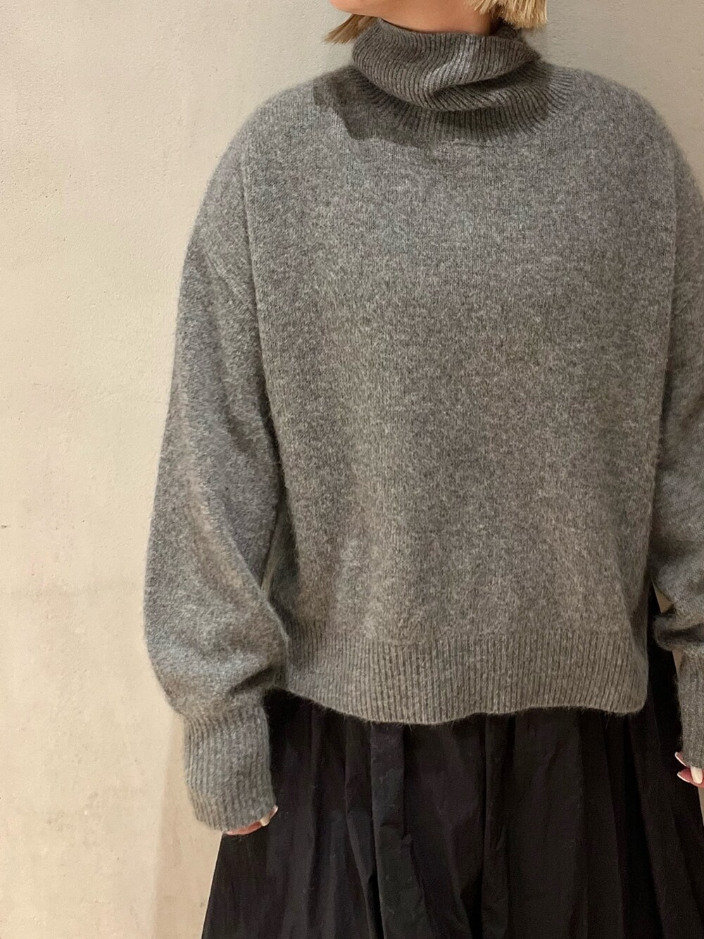 グレー系のニット/セーター、ブラック系のスカート、ブラック系のブーツを着用したレディースの冬コーディネートの7枚目の写真