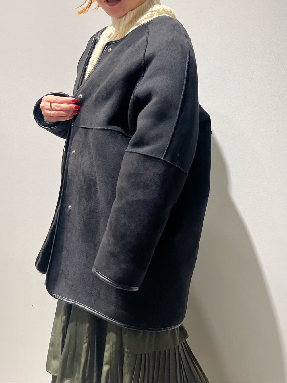 ブラック系のその他アウター、ホワイト系のニット/セーター、グリーン系のスカートを着用したレディースの秋コーディネートの7枚目の写真