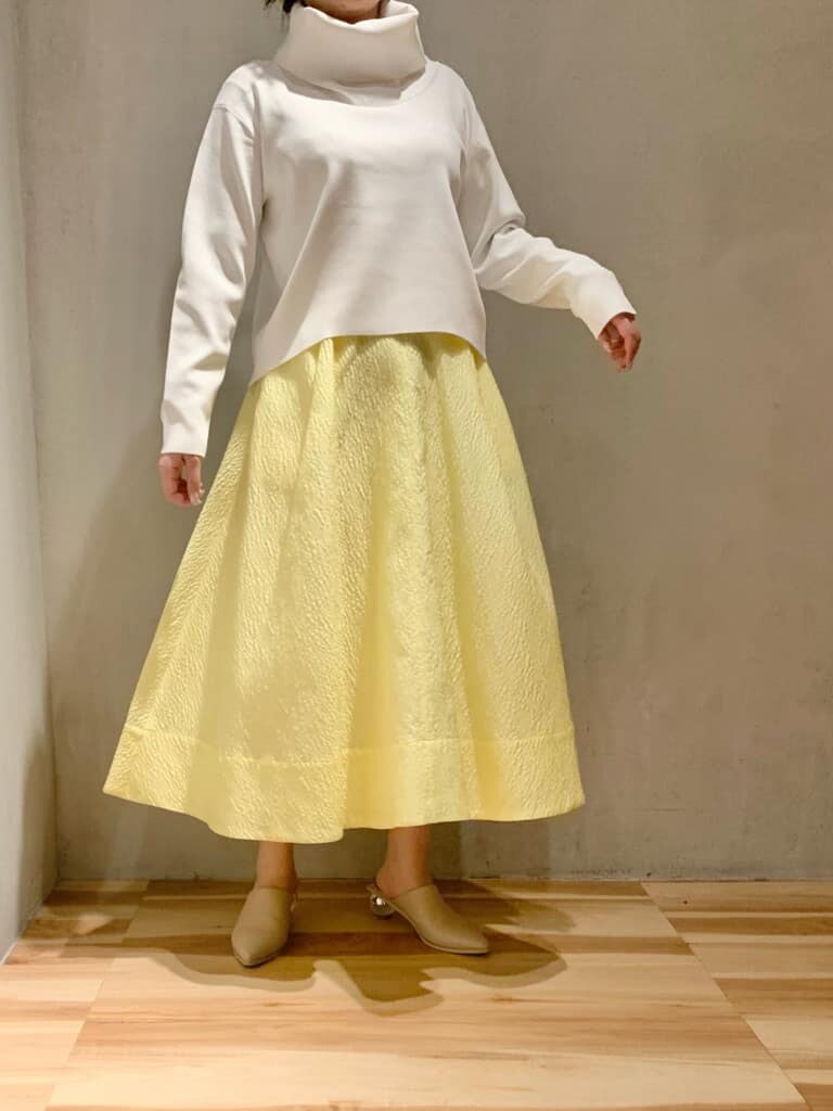 イエロー系のスカート、ホワイト系のニット/セーターを着用したレディースの冬コーディネートの2枚目の写真
