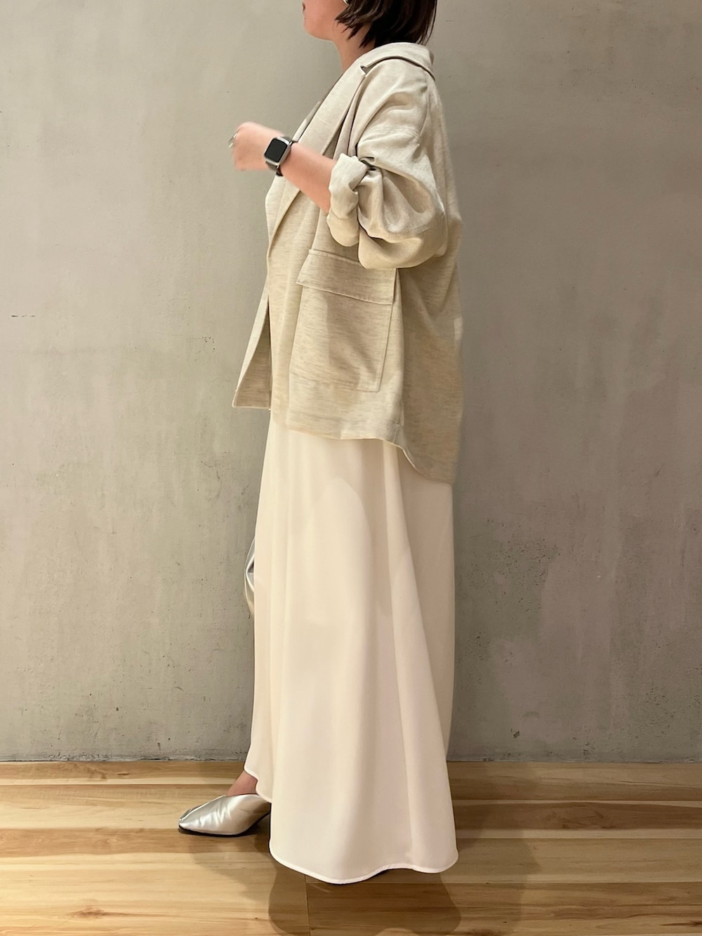 ベージュ系のテーラードジャケット、ホワイト系のワンピース、シルバー系のショルダーバッグを着用したレディースの春コーディネートの3枚目の写真