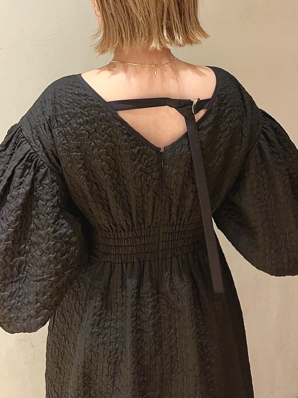 ブラック系のサンダル、ブラック系のワンピース、ゴールド系のネックレスを着用したレディースの冬コーディネートの8枚目の写真