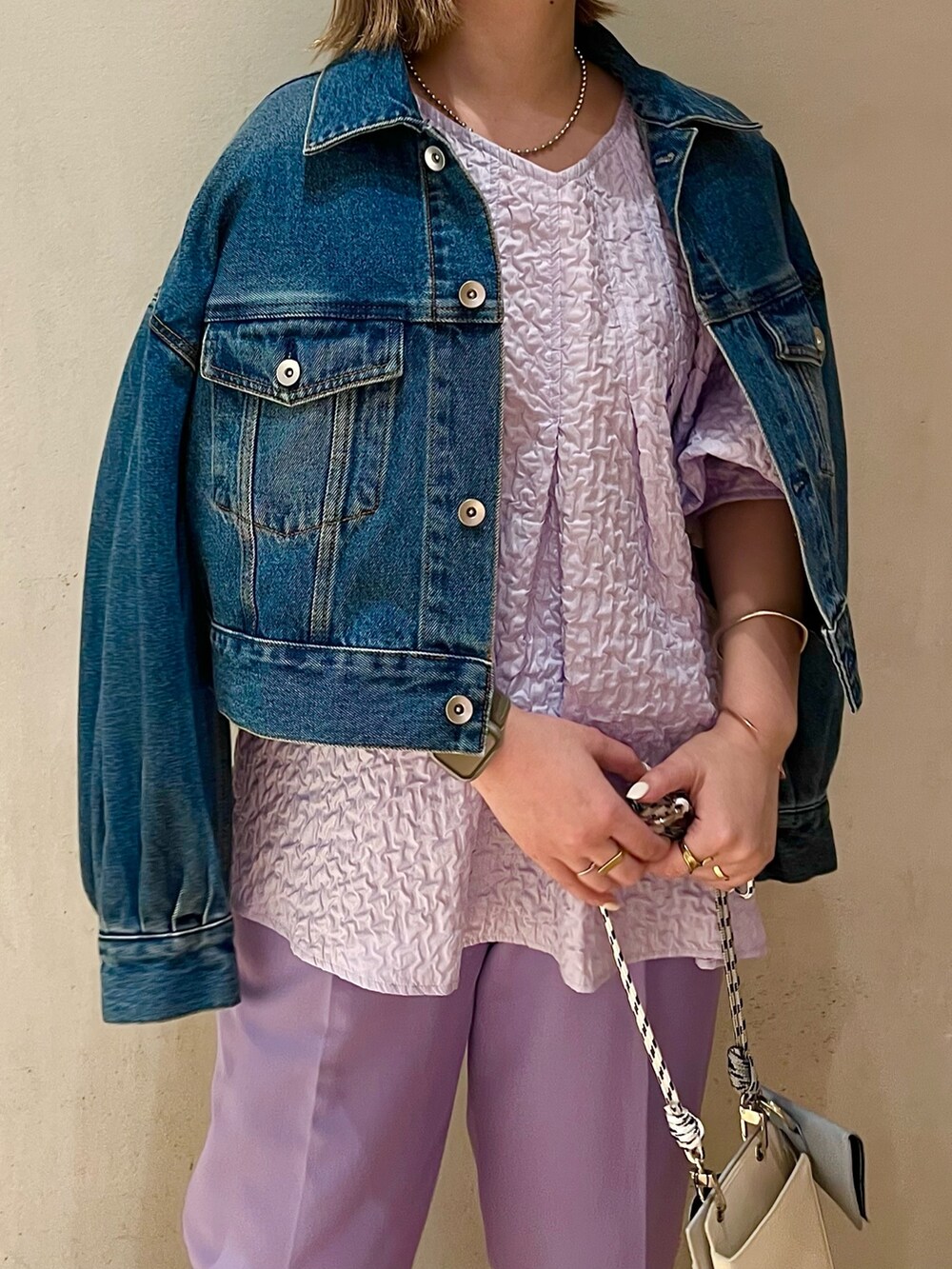 グレー系のショルダーバッグ、ブルー系のデニムジャケット、パープル系のその他パンツを着用したレディースの冬コーディネートの3枚目の写真