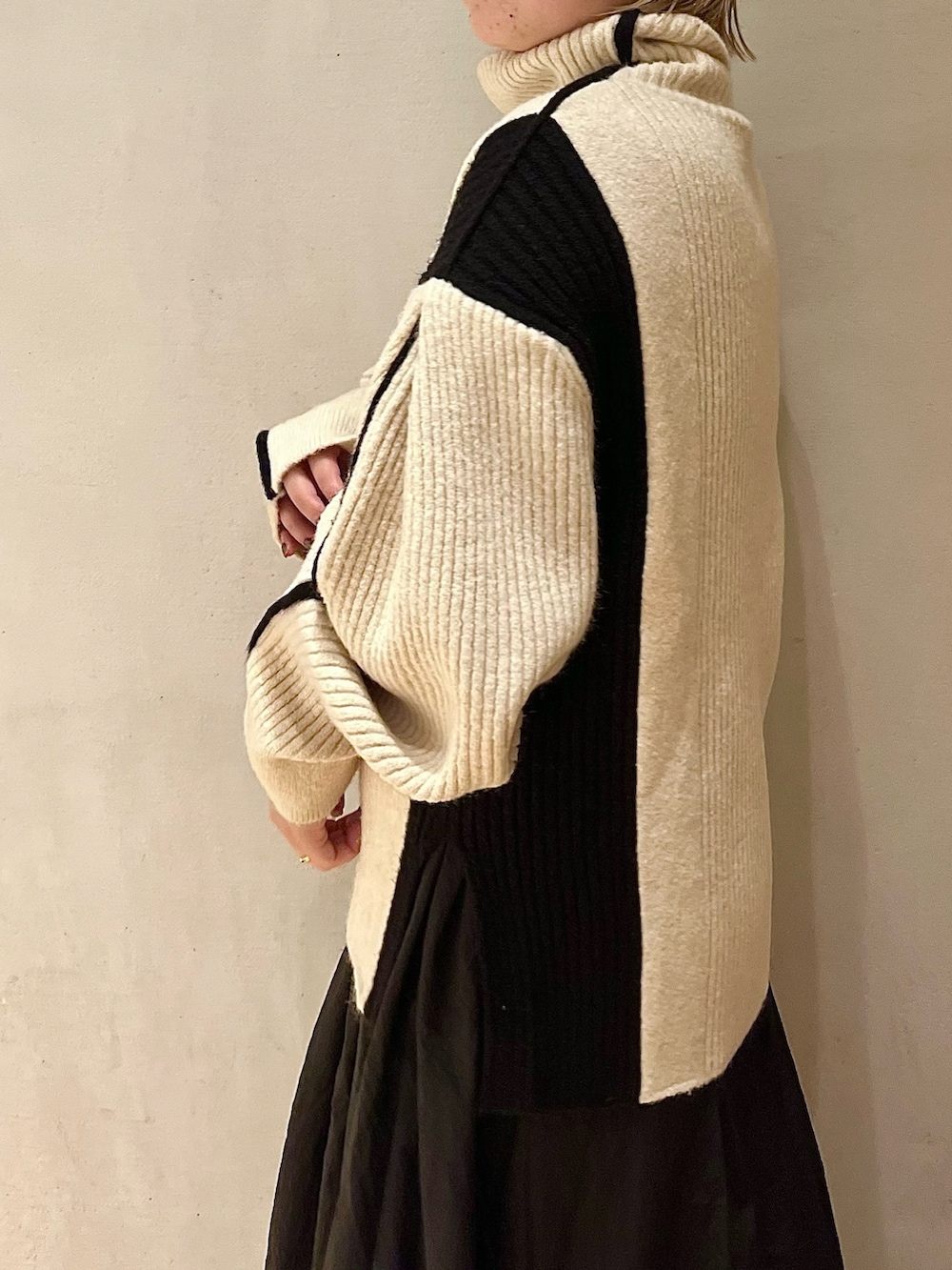 ブラック系のスカート、ホワイト系のニット/セーター、ブラック系のブーツを着用したレディースの秋コーディネートの6枚目の写真