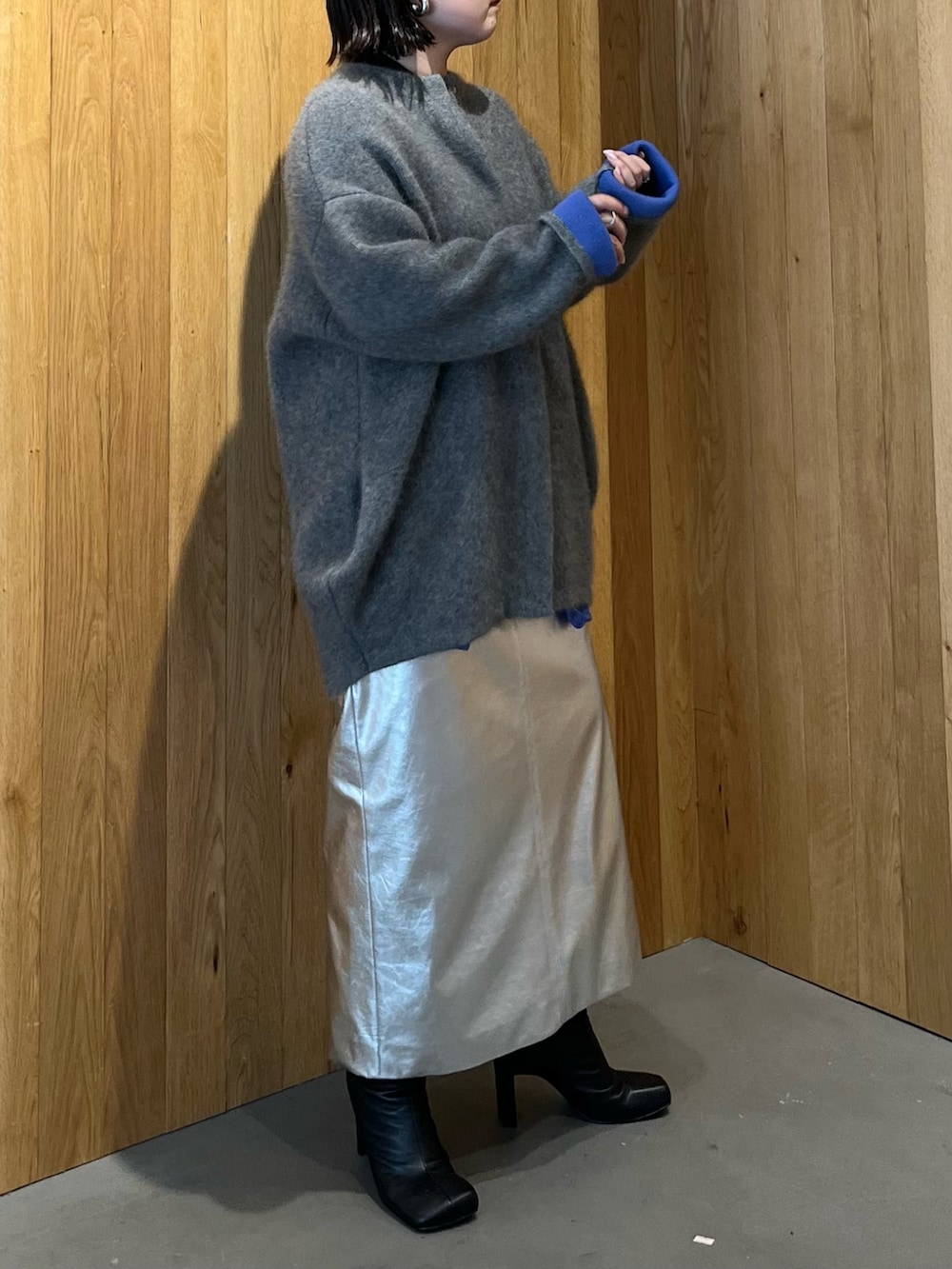 グレー系のカーディガン/ボレロ、シルバー系のスカート、ブラック系のブーツを着用したレディースの秋コーディネートの4枚目の写真