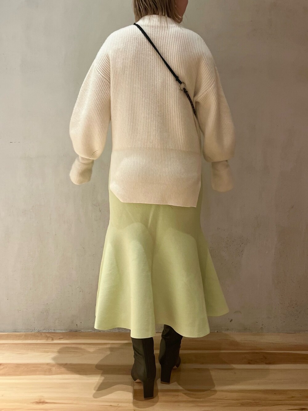 ホワイト系のニット/セーター、ベージュ系のショルダーバッグ、グリーン系のスカートを着用したレディースの冬コーディネートの3枚目の写真