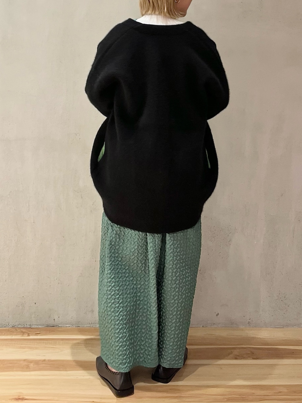 ブラック系のノーカラージャケット、グリーン系のジャンパースカート、ホワイト系のニット/セーターを着用したレディースの秋コーディネートの3枚目の写真