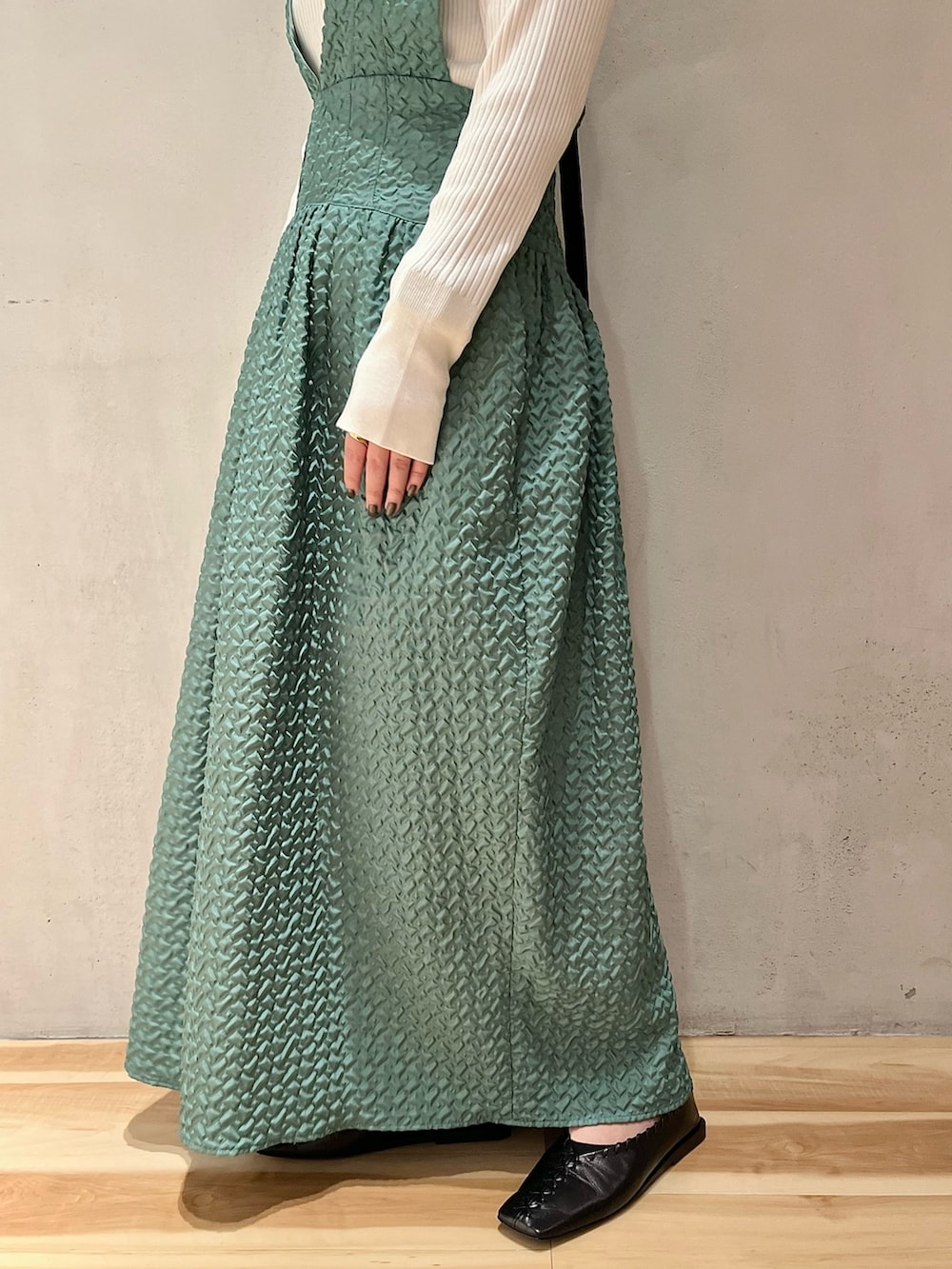 ブラック系のノーカラージャケット、グリーン系のジャンパースカート、ホワイト系のニット/セーターを着用したレディースの秋コーディネートの10枚目の写真