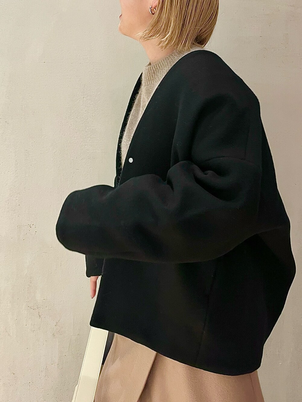 ブラック系のノーカラーコート、ベージュ系のニット/セーター、ベージュ系のスカートを着用したレディースの秋コーディネートの6枚目の写真