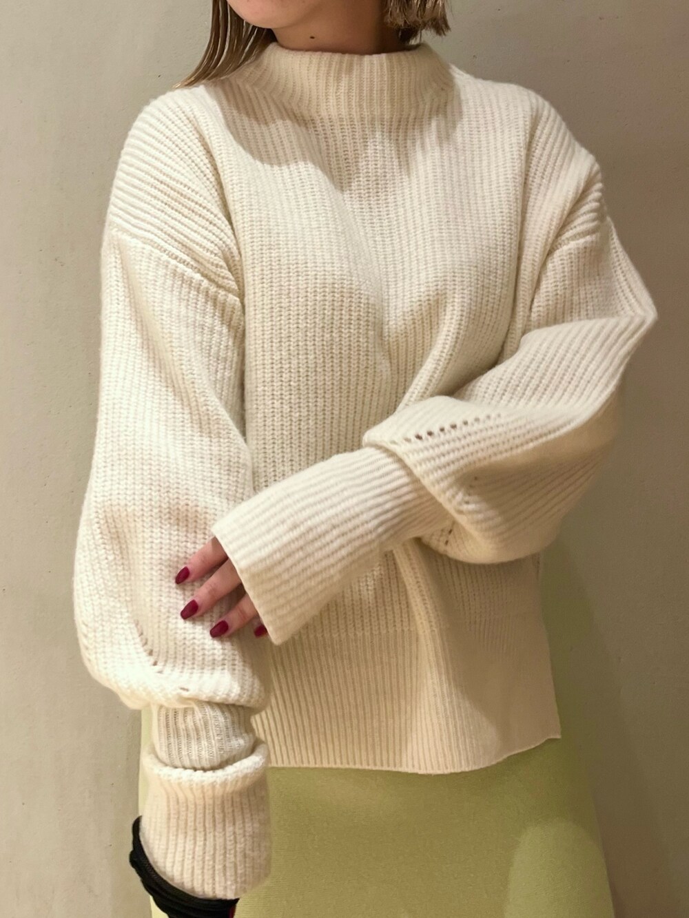 ホワイト系のニット/セーター、ベージュ系のショルダーバッグ、グリーン系のスカートを着用したレディースの冬コーディネートの4枚目の写真