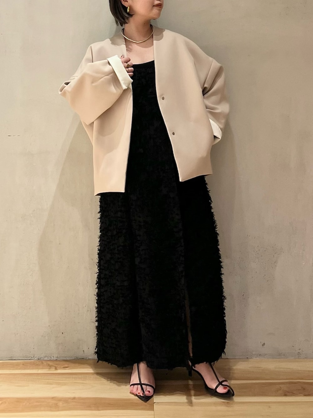 ブラック系のワンピース、ブラック系のタンクトップ、ベージュ系のノーカラーコートを着用したレディースの春コーディネートの4枚目の写真