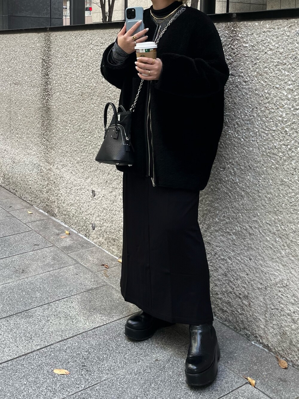 ブラック系のノーカラーコート、シルバー系のTシャツ/カットソー、ブラック系のブーツを着用したレディースの冬コーディネートの4枚目の写真