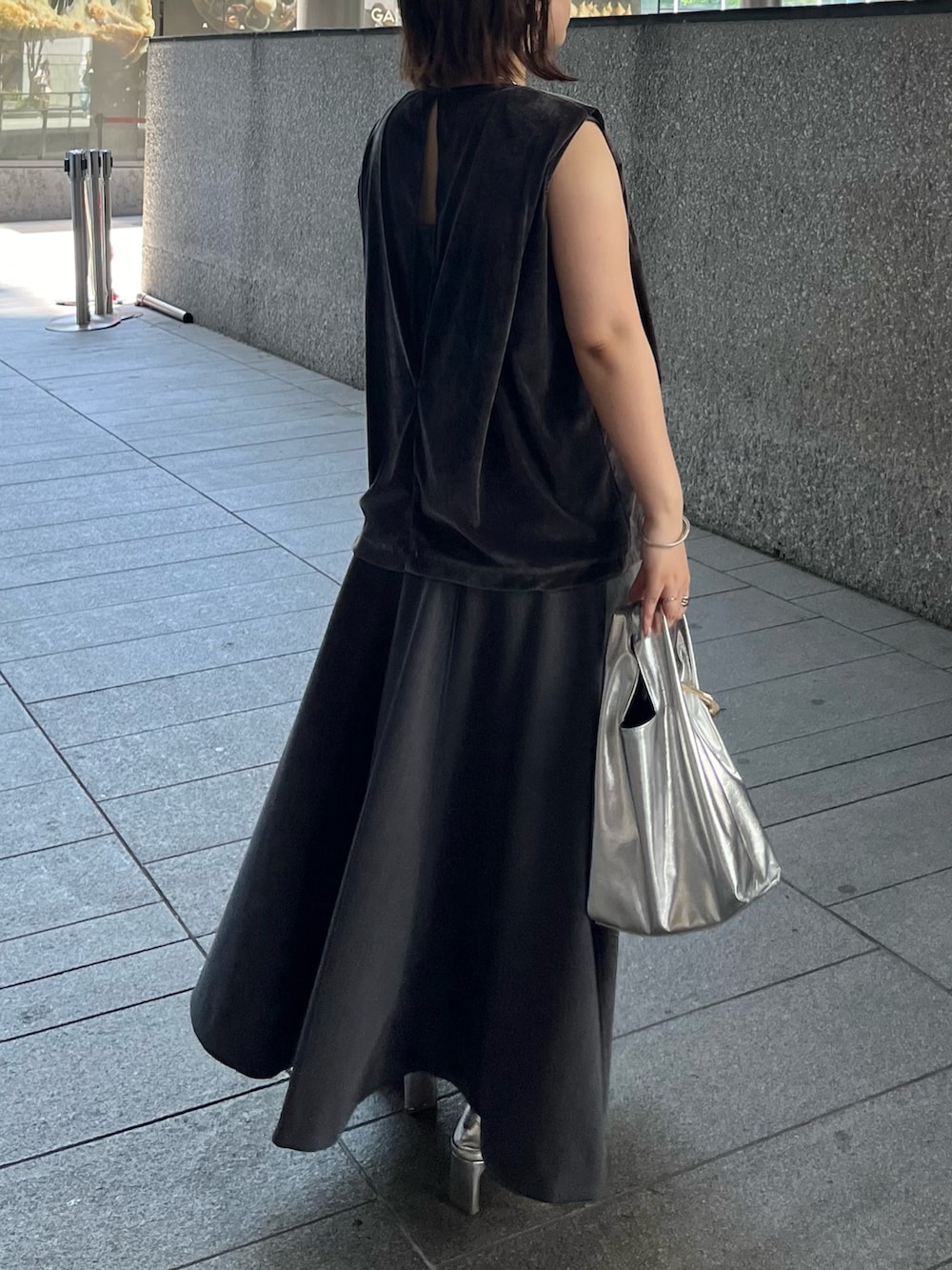 グレー系のスカート、ゴールド系のハンドバッグ、グレー系のTシャツ/カットソーを着用したレディースの夏コーディネートの5枚目の写真