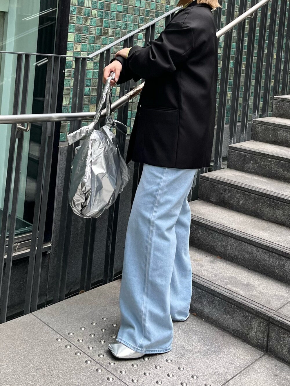 ブラック系のテーラードジャケット、イエロー系のニット/セーター、ブルー系のデニムパンツを着用したレディースの冬コーディネートの5枚目の写真