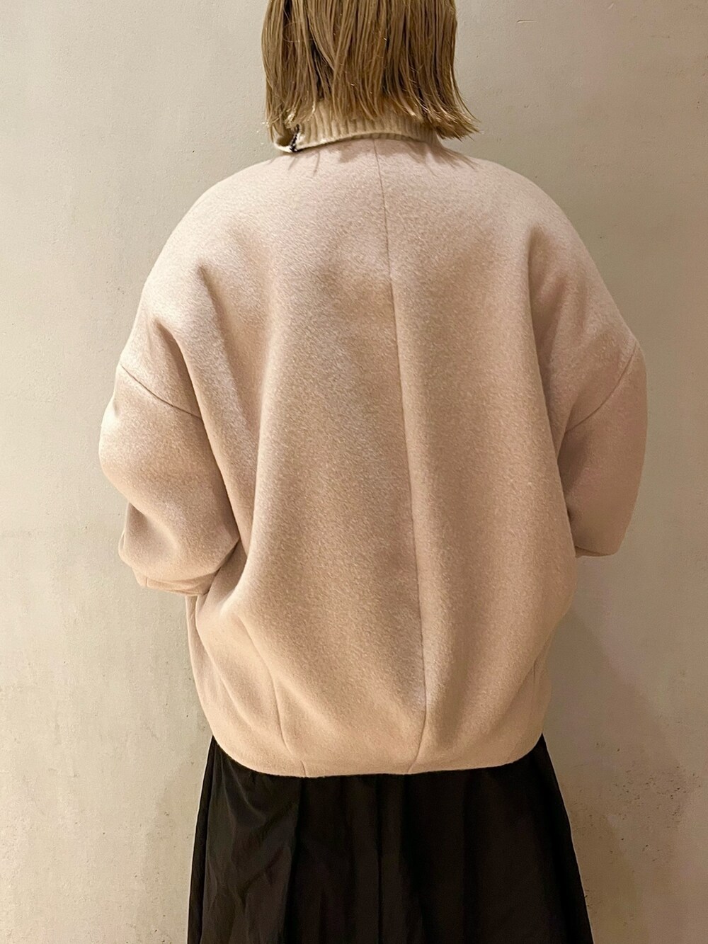 ベージュ系のノーカラーコート、ブラック系のスカート、ブラック系のブーツを着用したレディースの夏コーディネートの7枚目の写真