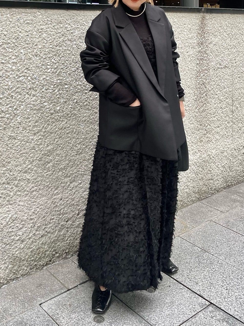 ブラック系のテーラードジャケット、ブラック系のニット/セーター、ブラック系のワンピースを着用したレディースの冬コーディネートの2枚目の写真