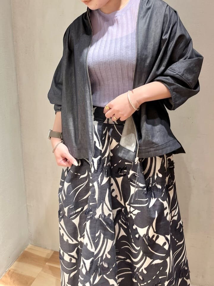 パープル系のニット/セーター、ブルー系のスカート、ブルー系のシャツ/ブラウスを着用したレディースの春コーディネートの3枚目の写真