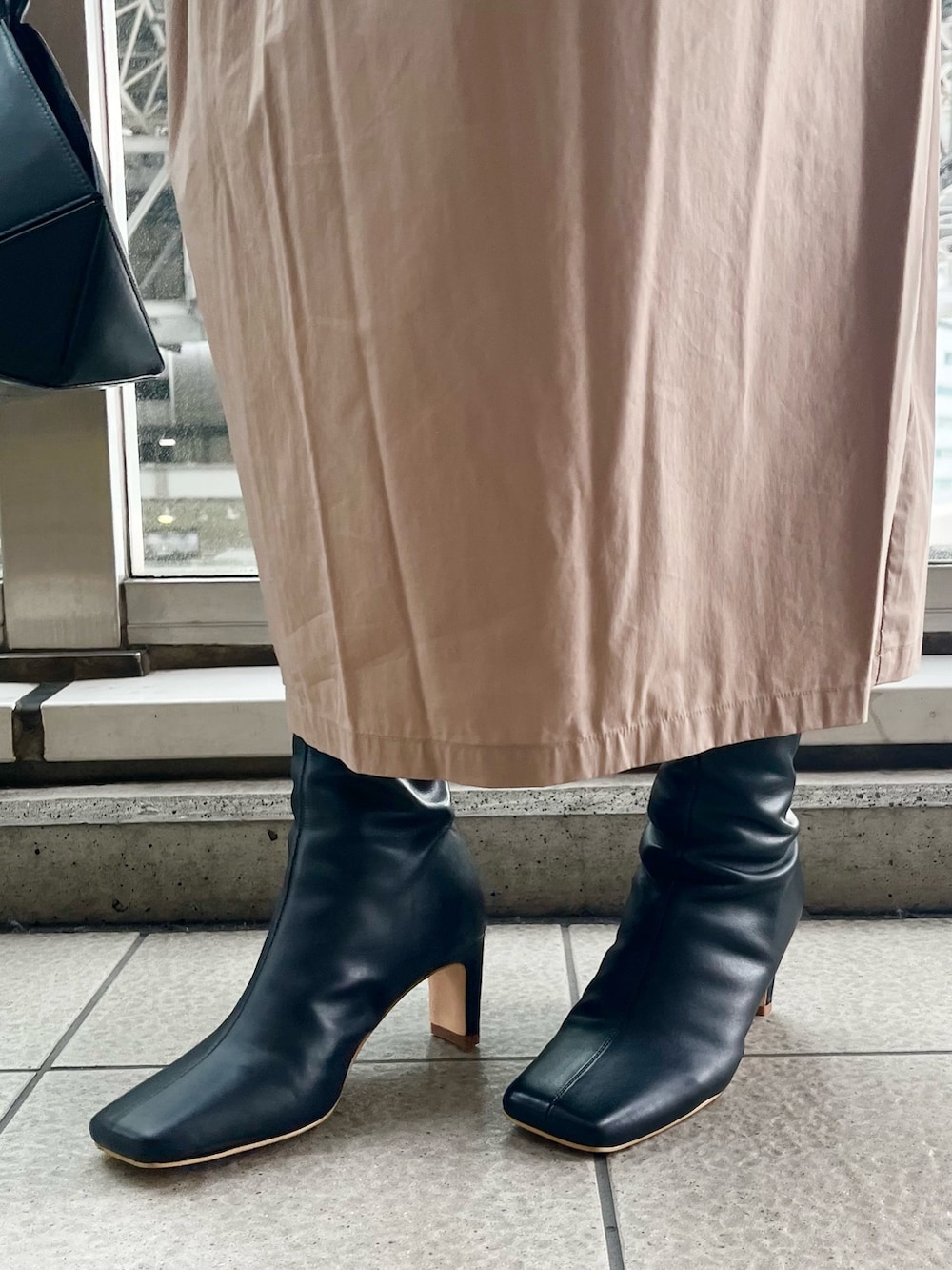 ブラック系のワンピース、ブラック系のハンドバッグ、ブラック系のブーツを着用したレディースの秋コーディネートの7枚目の写真