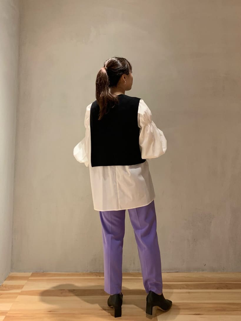 パープル系のスラックス、ホワイト系のニット/セーター、ブラック系のブーツを着用したレディースの秋コーディネートの2枚目の写真