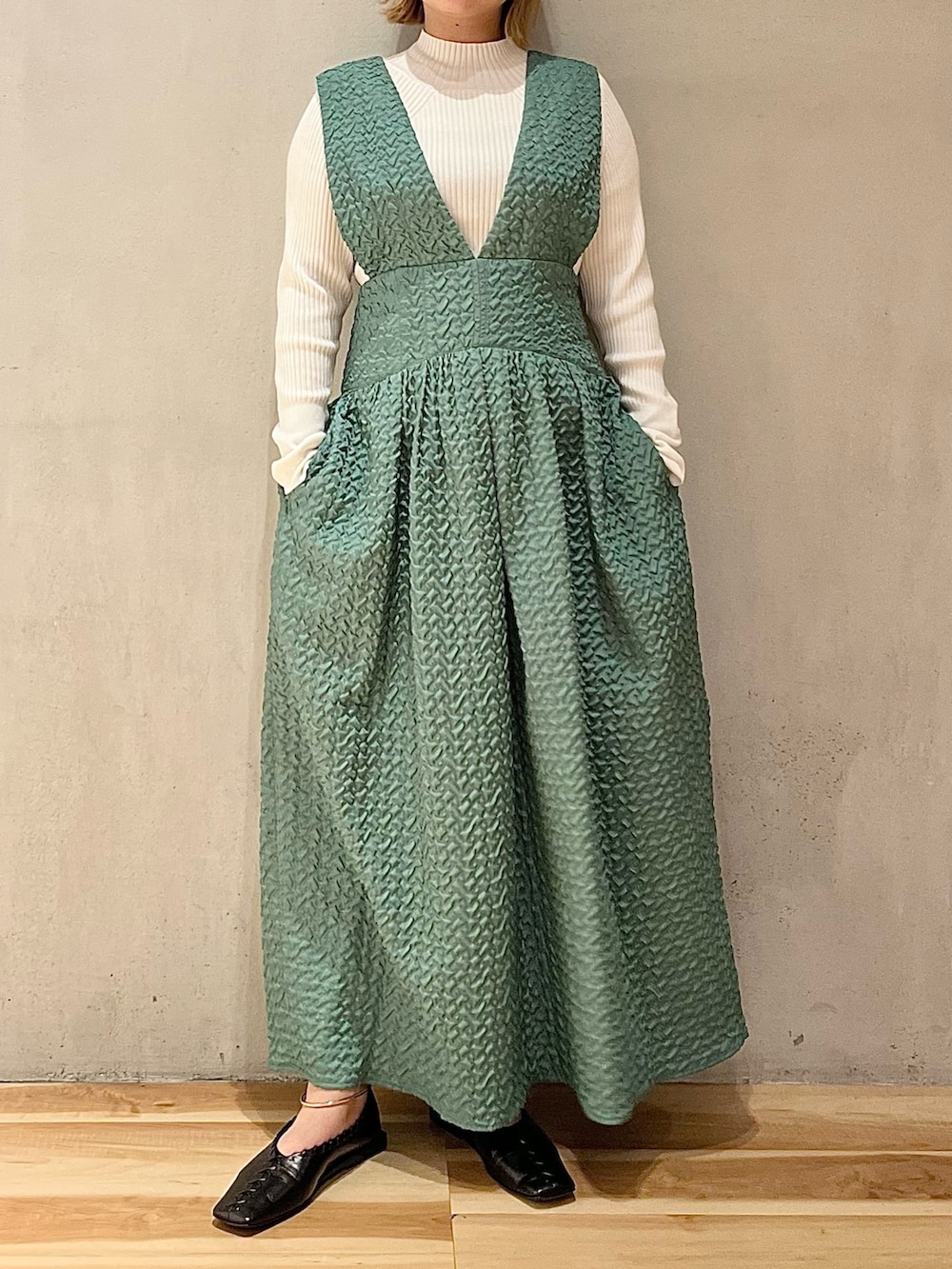 ブラック系のノーカラージャケット、グリーン系のジャンパースカート、ホワイト系のニット/セーターを着用したレディースの秋コーディネートの7枚目の写真