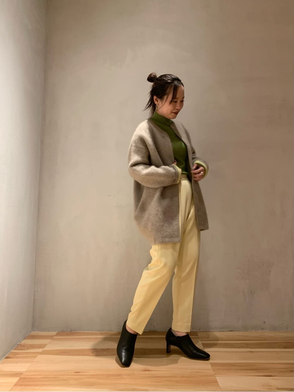 ブラック系のブーツ、イエロー系のスラックス、ブラウン系のカーディガン/ボレロを着用したレディースの秋コーディネートの4枚目の写真