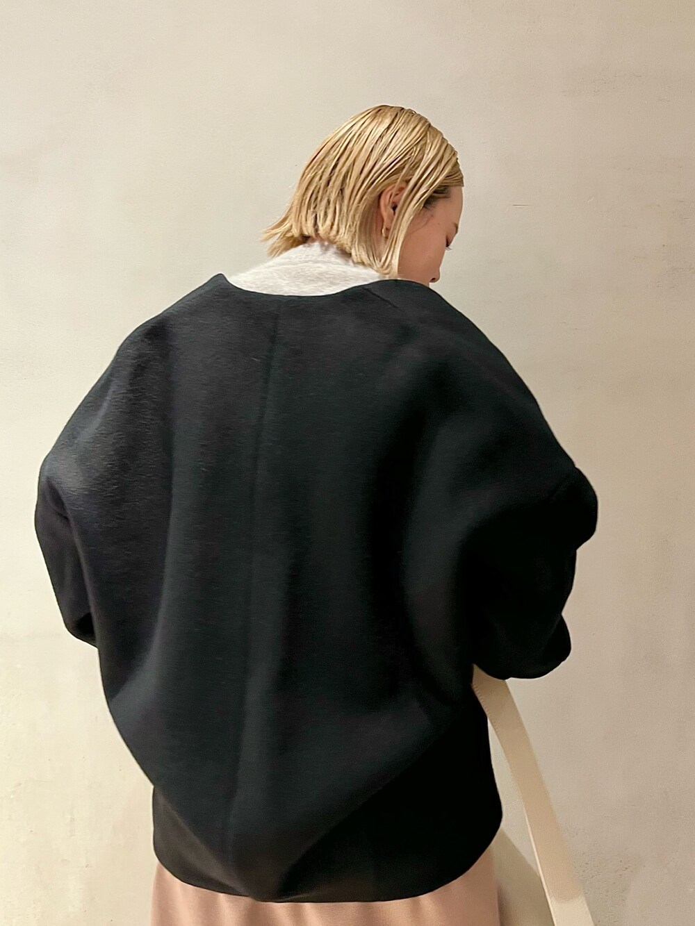 ブラック系のノーカラーコート、ベージュ系のニット/セーター、ベージュ系のスカートを着用したレディースの秋コーディネートの7枚目の写真