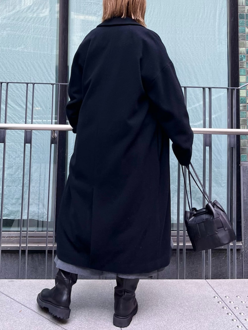 ピンク系のニット/セーター、ブラック系のチェスターコート、グレー系のスカートを着用したレディースの冬コーディネートの6枚目の写真