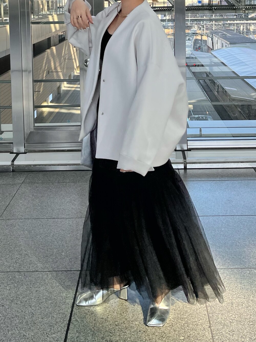 ベージュ系のノーカラーコート、ブラック系のタンクトップ、ブラック系のスカートを着用したレディースの冬コーディネートの5枚目の写真