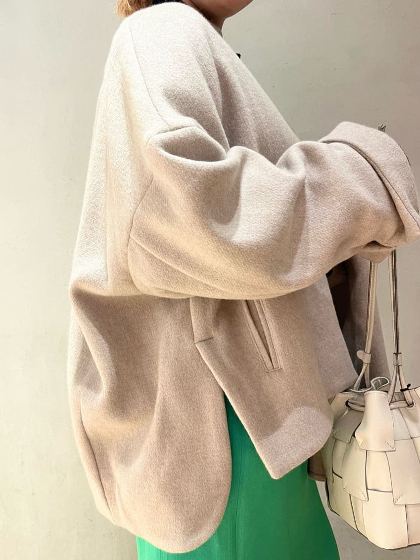 グリーン系のスカート、ベージュ系のノーカラーコート、ブラック系のニット/セーターを着用したレディースの秋コーディネートの6枚目の写真